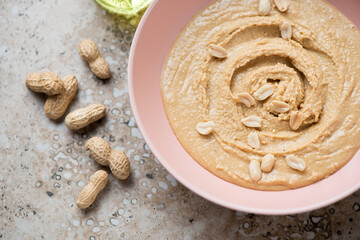 Roseate bowl with peanut butter or paste made from ground, dry-roasted peanuts, middle closeup, horizontal shot