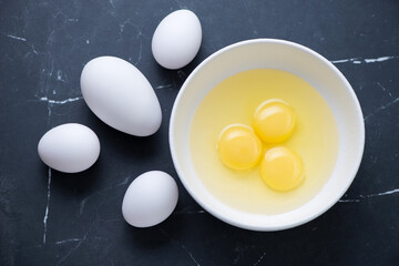 Fresh uncooked goose and chicken eggs on a black marble background, horizontal shot, above view