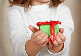 Little hands of the child holding Christmas present.