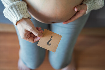 Concept of choosing baby name, Pregnant woman holding paper with question mark.