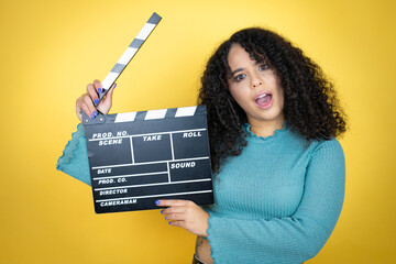 African american woman wearing casual sweater over yellow background holding clapperboard very happy having fun