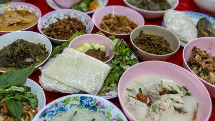 Close-up view of sticky rice, curry, laab, stir-fry and many other dishes packed in bowls.
