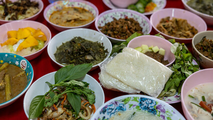 Close-up view of sticky rice, curry, laab, stir-fry and many other dishes packed in bowls.