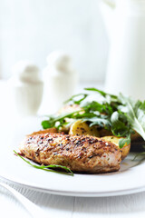 Grilled Chicken Breast with oven baked potatoes and fresh rocket. Bright background. Close up.