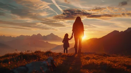 A woman and a child standing on a hill at sunset. Perfect for family or nature concepts © Fotograf