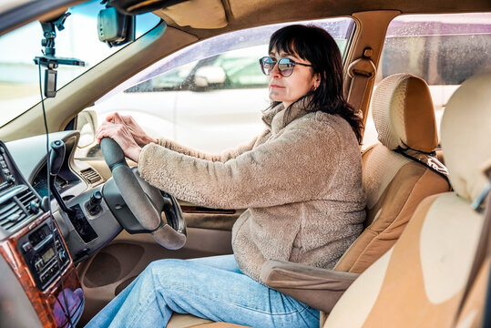 Young attractive 49 years old woman in jacket looking away, driving the car