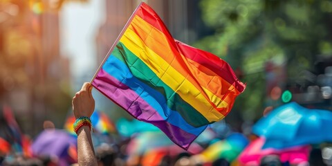 arm and hand holding a colorful rainbow flag in the sun