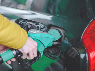 The hand of a young caucasian guy refuels the car with gasoline.