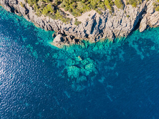 Rocky cliff edge with rocks in the blue sea.