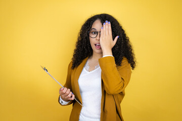 African american business woman with paperwork in hands over yellow background covering one eye...