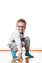 A young boy with glasses crawling on the floor