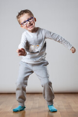 A young boy wearing glasses and a white shirt is looking at the camera. Fooling around having fun time.