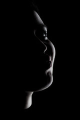 Side lit silhouette portrait of a girl against black background