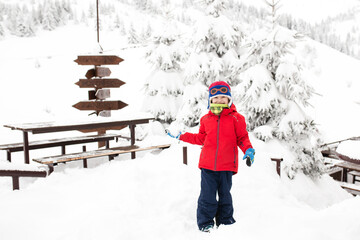 Little boy on a cold winter day in the mountains. Playing with snow. Throwing snow balls.