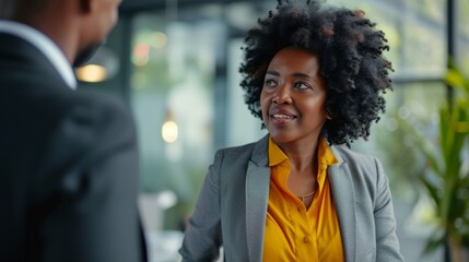 Black businesswoman communicating with mature colleague while going through office