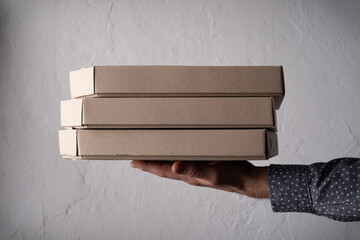 Caucasian male hands hold three pizza boxes side view with copy-space