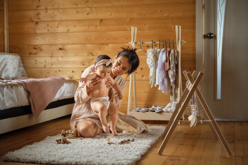 Mother gently dressing her baby, a cozy nursery behind. This tender routine speaks to the loving...