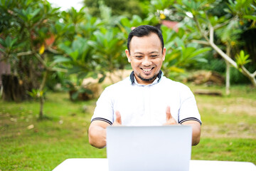 Asian man's expression in front of laptop. Asian man is online with laptop