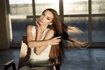 Brunette woman sitting on a chair and brushing her hair