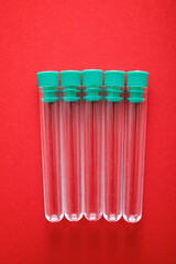 Five plastic test tubes on a red surface - 784497399