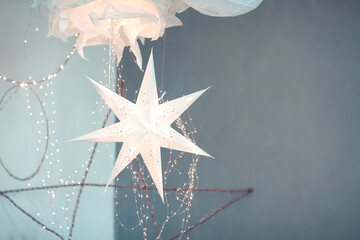 Delicate paper decorations and light garlands hanging against wall