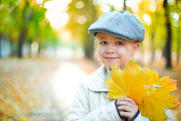 Child holding yellow and red leaves. Little girl with maple leaves.
