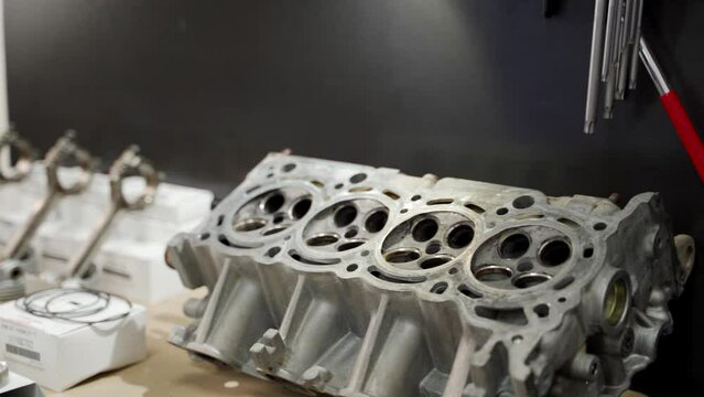 Auto mechanic assembles engine using new piston, rings, liner kit. Workshop scene rebuilds motor, upgrades components. Professional service fits parts, maintains vehicle performance, durability.