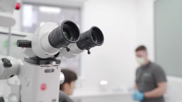 Dental microscope in modern dentistry office. Dentist preparing patient for operation. Using microscope for root canal treatment. Endodontist explains treatment process in the dental clinic.