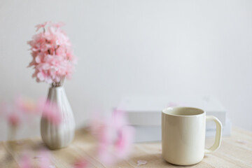 テーブルに置かれた桜の花瓶とマグカップと本