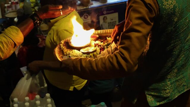 devotee offering holy oil lamp aarti to visitors at night