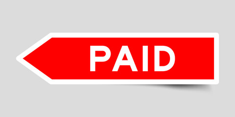 Red color arrow shape sticker label with word paid on gray background