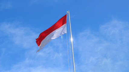 The Indonesian flag flutters againts the background of bright blue sky.. Independence day concept