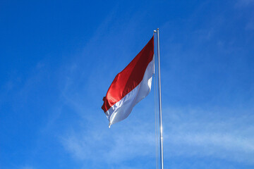 The Indonesian flag flutters againts the background of bright blue sky.. Independence day concept