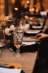 Selective focus on tall glass with white wine standing on dinner table after festive banquette