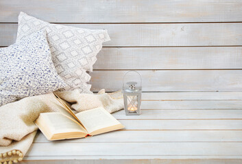 Cozy still life with lantern, pillows, book and plaid