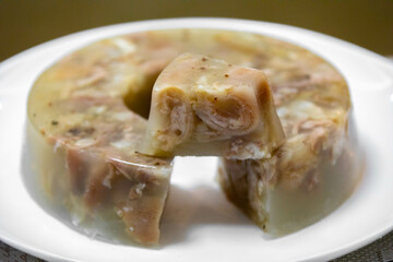 Traditional Ukrainian festive cold appetizer. Pork jelly with pieces of meat with parsley isolated on a white background. Drehlhi