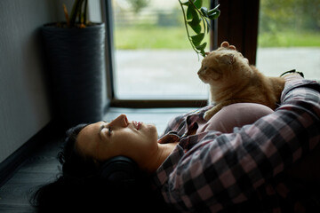 Woman Relaxing on Floor With a Playful Cat by a Sunny Window Sill