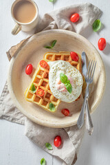 Homemade waffles with with fried eggs, tomatoes and basil.