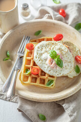Tasty and waffles with with fried eggs, tomatoes and basil.
