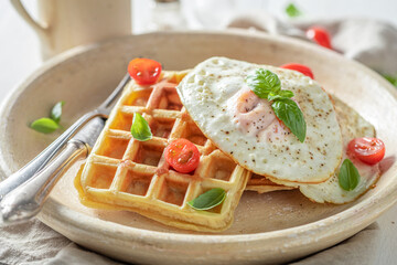 Hot waffles with with cherry tomatoes and fried eggs.