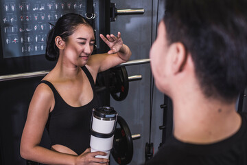 A young asian woman politely expresses her disinterest to talk to a man who approached her while at the gym. Declining a date, emphasizing personal boundaries during exercise. - obrazy, fototapety, plakaty