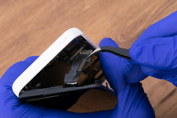 hands of a smartphone repairman opening the phone to identify the problem and replace the faulty...