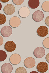 Frame with eye shadow beige brown natural color on neutral background with copyspace. Shiny and matte swatches of eyeshadows powder for make up, minimal style photo pastel colored, above view