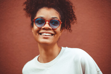 African ethnicity young woman in stylish sunglasses, with curly hair tied up in high ponytail,...