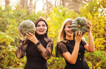 Two female friends holding scary green pumpkins in front of her face