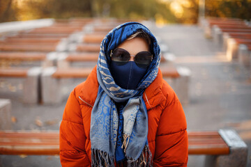 Woman in mask and outerwear in park