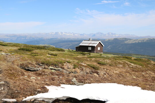 Cabin by the foot of Saukampen with goats grassing around and view of Rondane in the backgorund