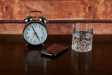 Alarm Clock with Mobile Phone and Glass of Water on a Bedside Shelf - 784557777