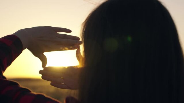 Hands of young female director cameraman making frame gesture at sunset in park. Seeing world as different. Business planning. Beautiful girl shows her fingers frame symbol, sun, Sees like in movies.