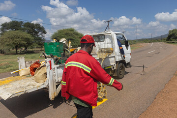 Obraz premium african men repairing and maintaining faded road markings on the highway, repainting yellow markings for traffic safety